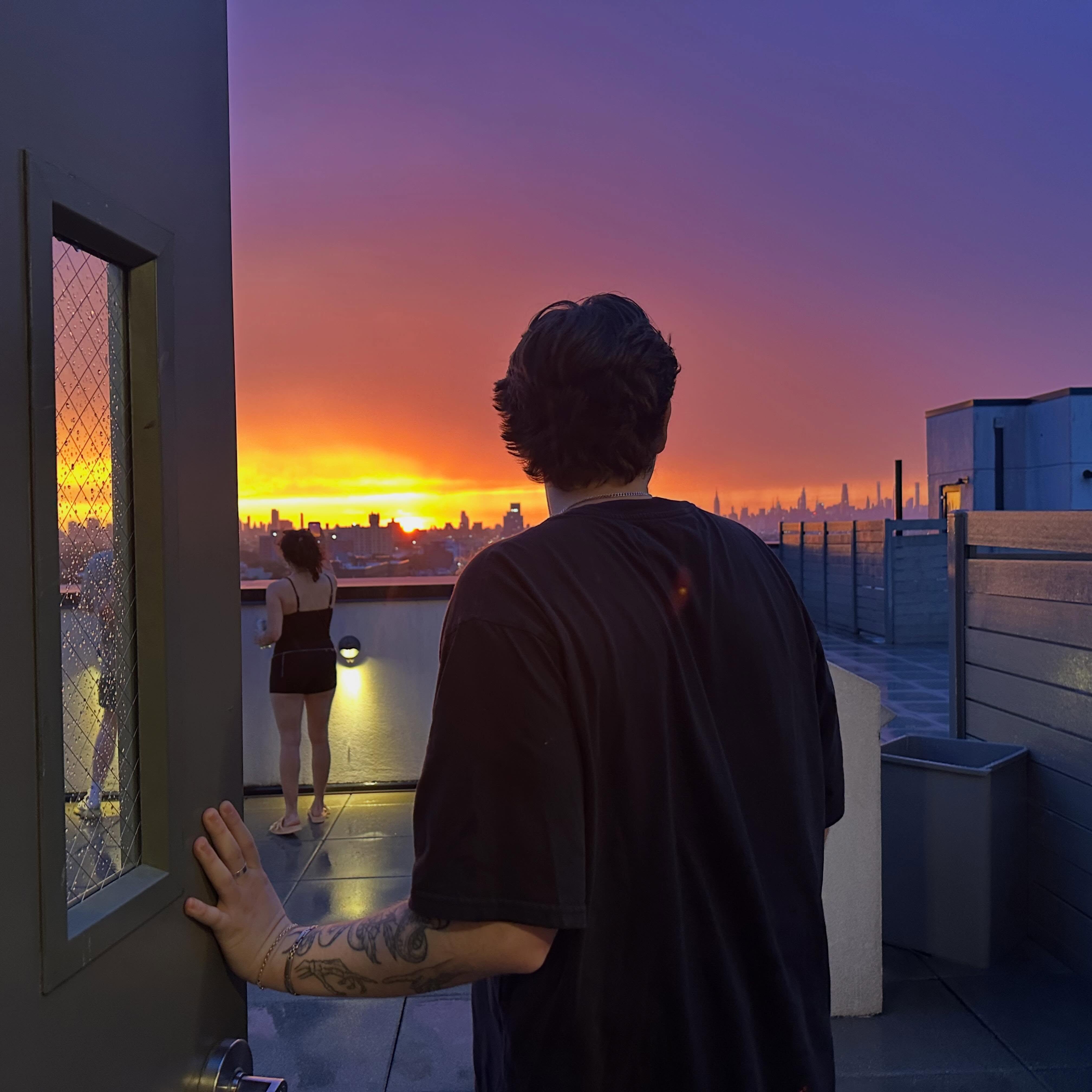 Kaden Meza on a rooftop at sunset, looking out over the New York City skyline